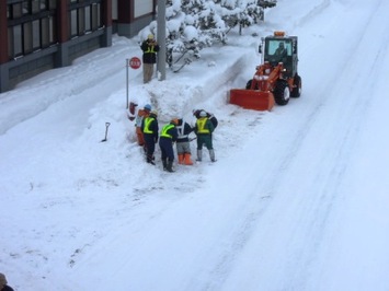 懸命に流雪溝へ投雪する方々の様子