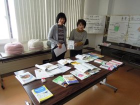 婦人之友 砂川友の会 2名の方に展示品を持って頂き記念撮影をしている様子